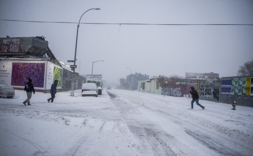 People cross the street during a snow storm in the Bushwick section of Brooklyn, N.Y., on Saturday.