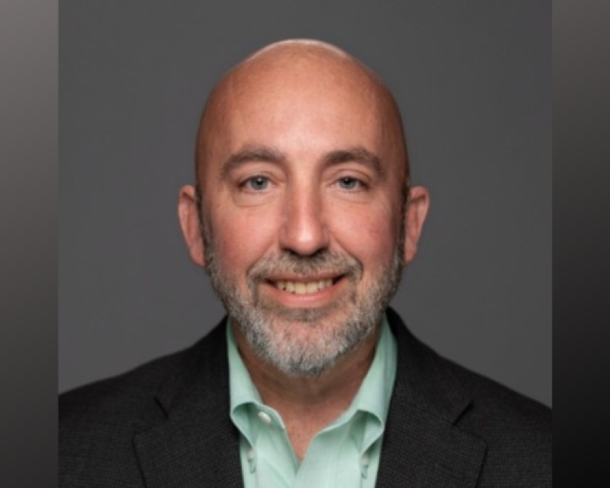 A photo portrait of a middle-aged man in a suit.