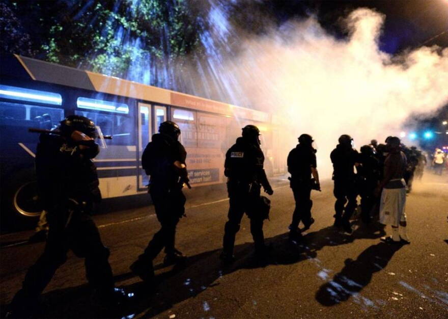 Charlotte-Mecklenburg police officers walk throught a haze of tear gas on Old Condord Rd. in Charlotte on Sept. 20.