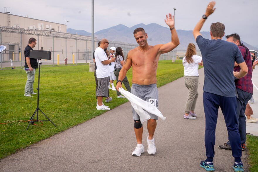 Inmate Casey Vanderhoef high-fives Rep. Paul Cutler as he crosses the finish line.