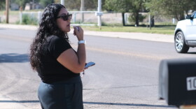 A woman stands beside the street leading to National Beef Tuesday, blowing a whistle and warning workers of federal immigration agents.