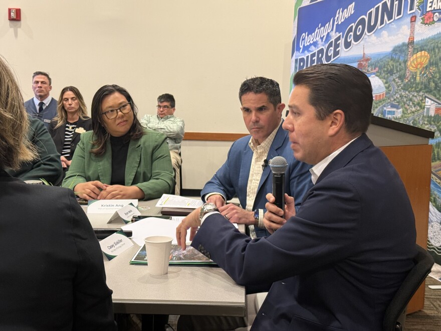 People sit around a table as a man speaks into a microphone.