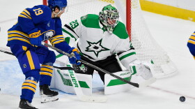 Buffalo Sabres center Peyton Krebs, left, and Dallas Stars goalie Jake Oettinger, right, reach for the puck during the third period of an NHL hockey game Thursday, Oct. 8, 2026, in Buffalo, N.Y. (AP Photo/Adrian Kraus)