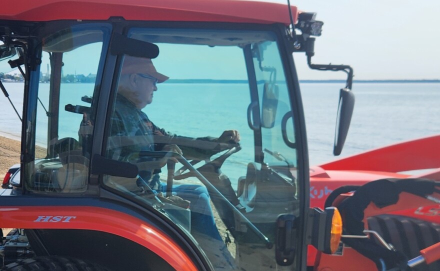 Jeff Johnston drives his tractor back and forth pulling debris from the shores using a method called "backblading" at Blair Street Pier in Alpena on Friday, July 24, 2026.
