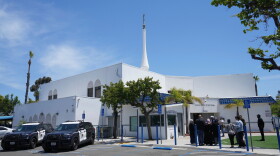 FILE - People gather as police vehicles are parked outside of the Islamic Center of San Diego, the day after a shooting, May 19, 2026, in San Diego.