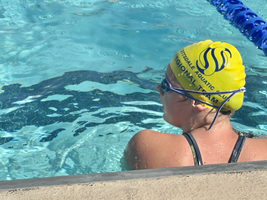 Woman in goggles and a yellow swim cap in a outdoor pool