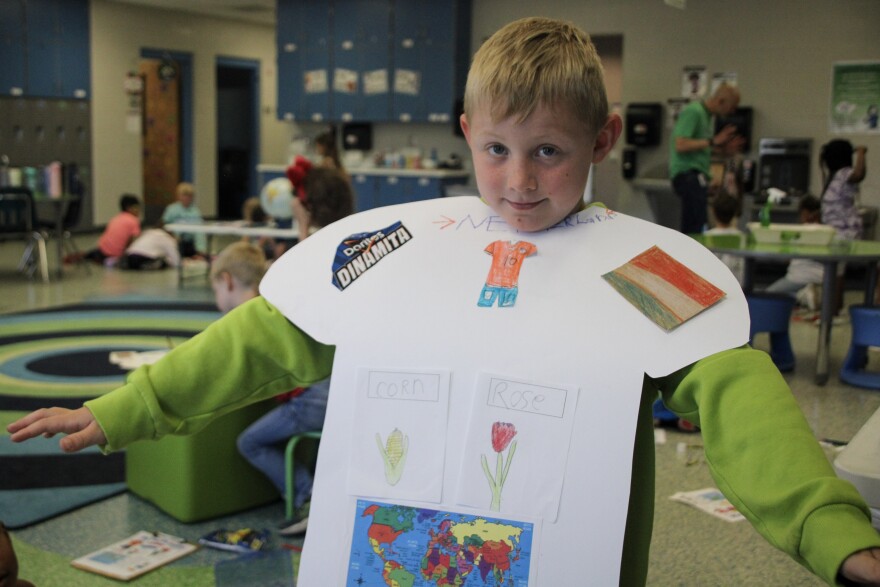First-grader Lenny Nash shows off his group's "jersey" collaged with information about their assigned team, the Netherlands, that will be playing in the World Cup.