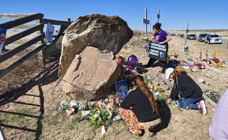 Protesters lay flowers to help rebuild a memorial for victims near the front gate of the Zorro Ranch, which had been torn down just days before Sunday's rally.