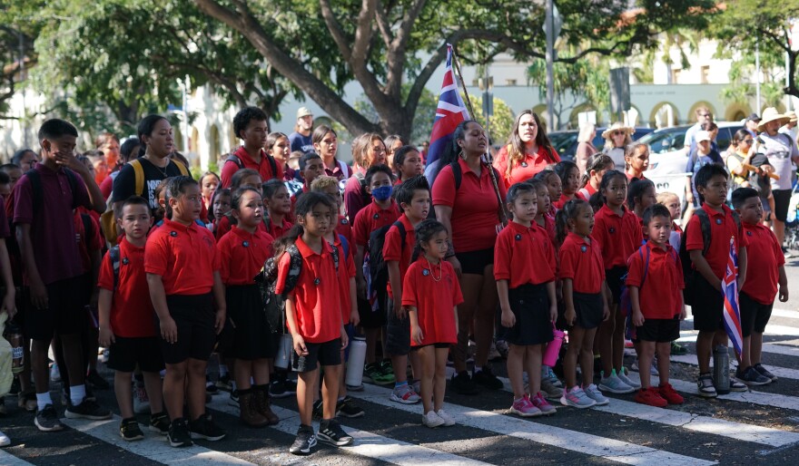 Students and teachers stand in front of the ʻIolani Palace gates and sing as they are welcomed in.