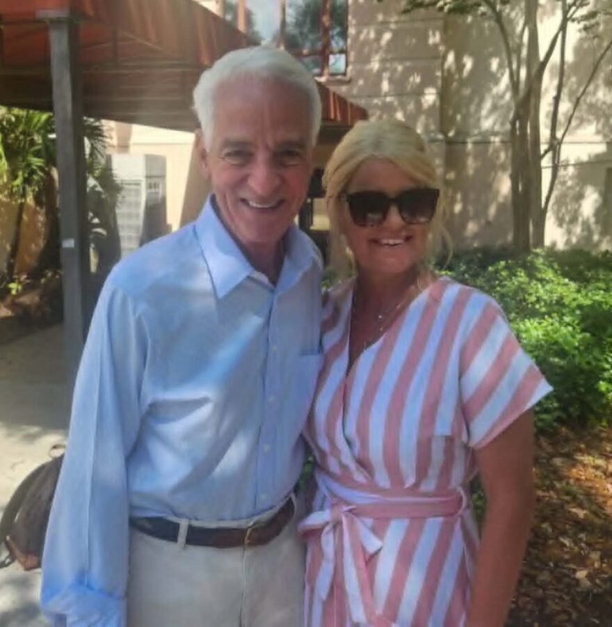 Man with grey hair stands next to blonde woman outside 