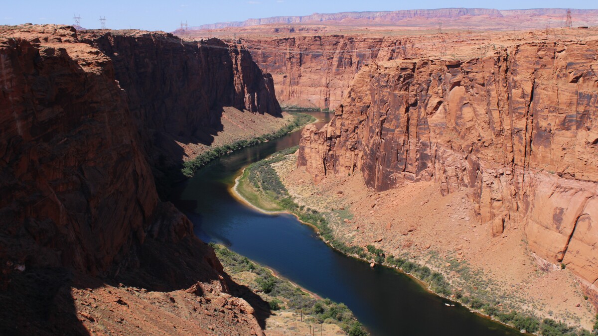 A wide river curves through a canyon of red rock cliffs