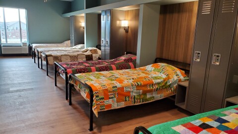 Beds with colorful blankets in a shelter for people experiencing homelessness.