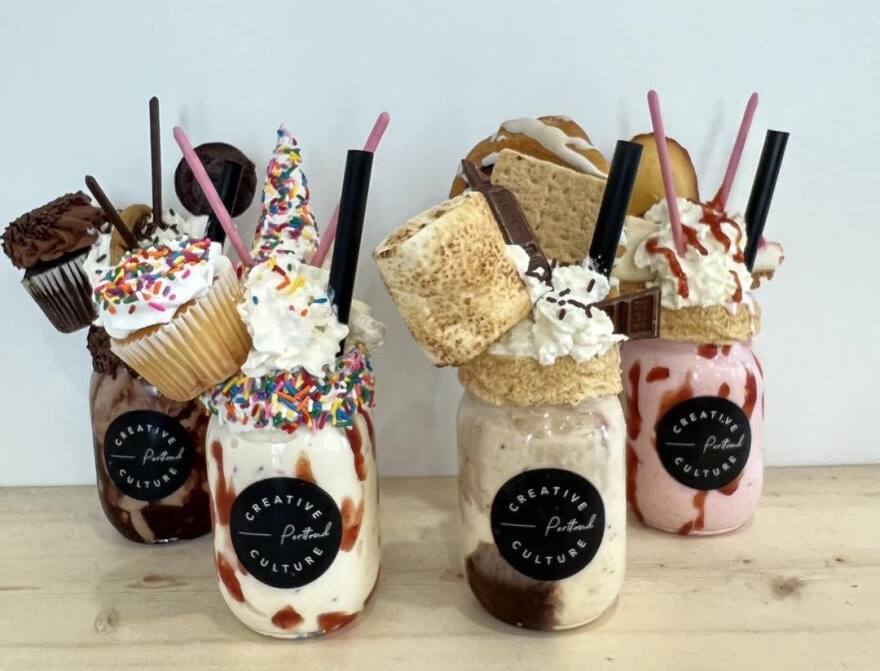 Four varieties of milkshake with toppings like cupcakes and toasted marshmallows. 