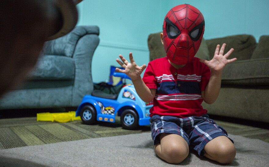 In this July 26, 2018 photo, a four-year-old boy is shown playing in a Spiderman mask, who is being cared for by Evelyn Zepeda at her home in Austin, Texas. 