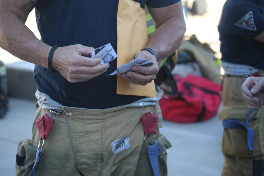 Firefighters pass out photos of the first responders who died at Ground Zero, pinning them to their jackets or securing them in their helmets.