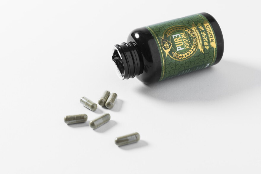 An open bottle of Kratom with capsules on a table