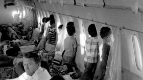 FILE - In this April 1975 file photo, orphans aboard the first "Operation Babylift" flight at the end of the Vietnam War look through the windows of World Airways DC-8 jet as it flies them to the United States. (AP Photo/File)
