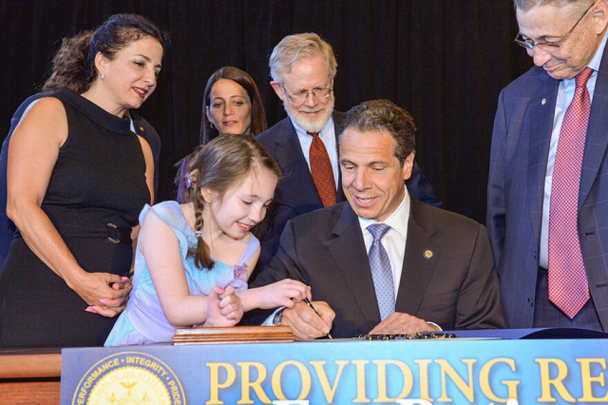 Governor Cuomo signs medical marijuana bill into law, with the help of Amanda Hauser, a young patient who will benefit. Background, left to right, Senator Diane Savino, Mary Anne Hauser, Assemblyman Dick Gottfried, Speaker Sheldon Silver