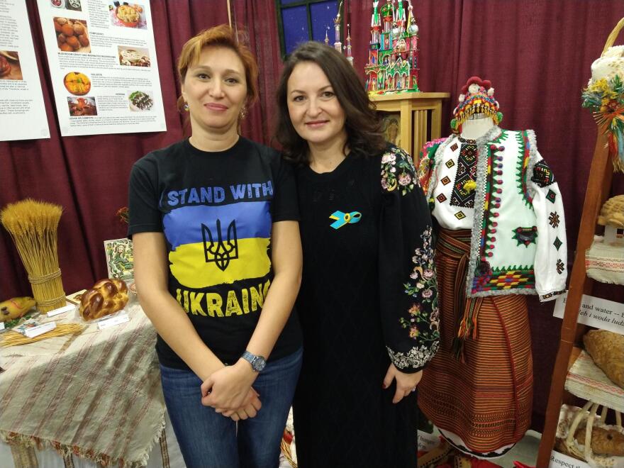 Dina Borysenko (left) and Halyna Salapata pose for a photo in front of Ukranian cultural items, while at the Holiday Folk Fair November 19.