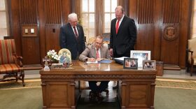 Gov. Mike Kehoe signs a bill banning non-disclosure agreements in child sex abuse cases on June 10, 2025, alongside the bill’s sponsors, state Rep. Tim Taylor, R-Bunceton, left, and state Sen. Kurtis Gregory, R-Marshall, right.