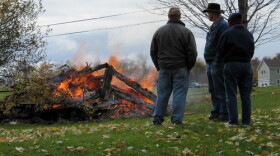 Larry Lago, left, and friends watch an old wood shed burn in northern New York.