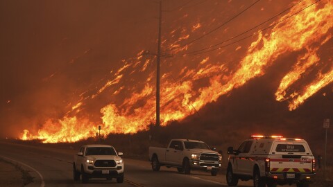 Firefighters monitor flames caused by the Hughes Fire along Castaic Lake in Castaic, Calif.