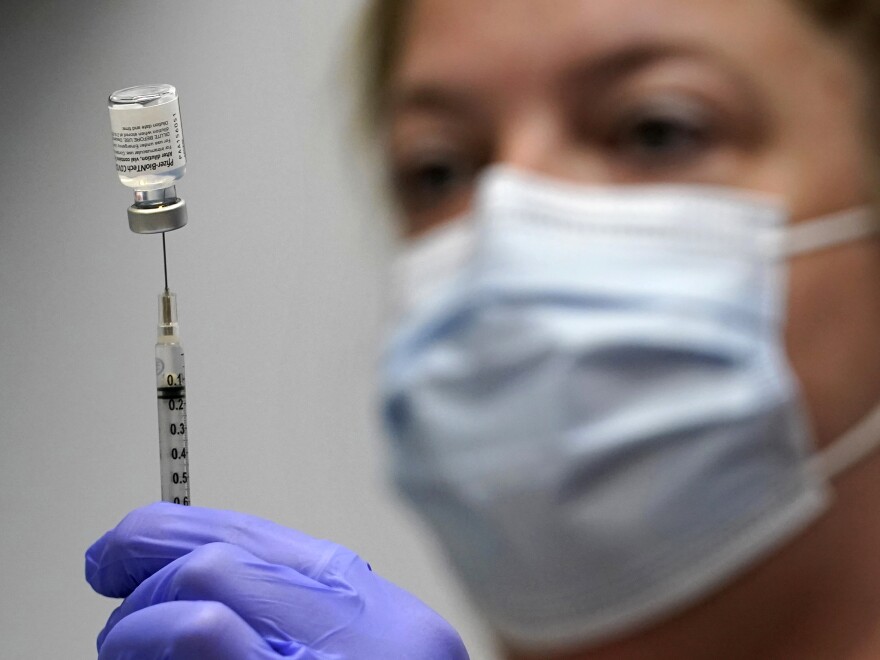 In this March photo, pharmacy technician Hollie Maloney loads a syringe with Pfizer's COVID-19 vaccine at the Portland Expo in Portland, Maine. The U.S. gave full approval to Pfizer and BioNTech's COVID-19 vaccine on Monday.