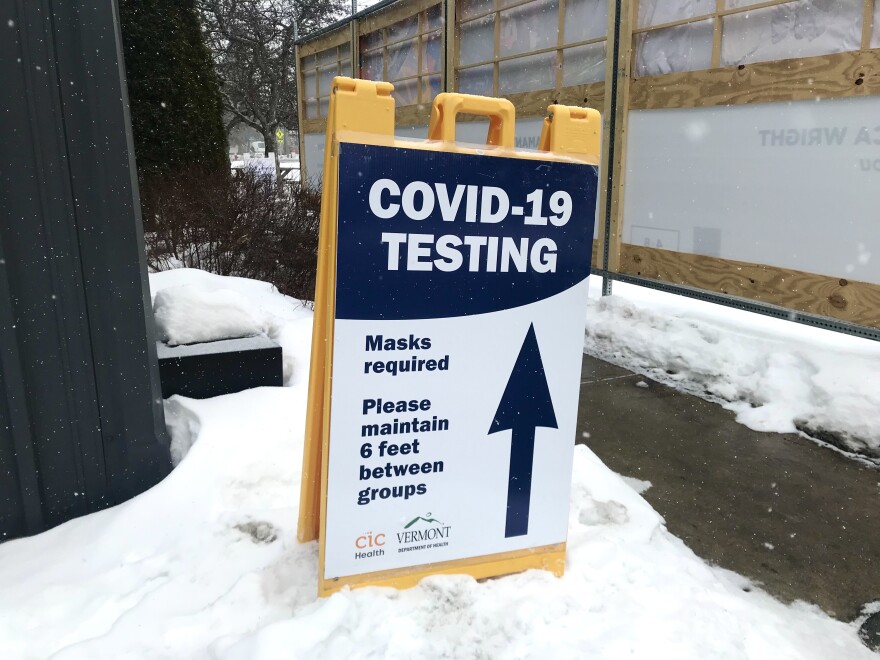 A sign reading COVID-19 testing along a snowy sidewalk