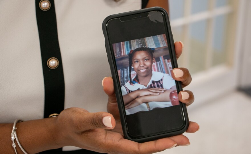 Crystal LaFrance, principal of The Leah Chase School, poses with a photo of herself when she was a student in the same building on Aug. 8, 2024.