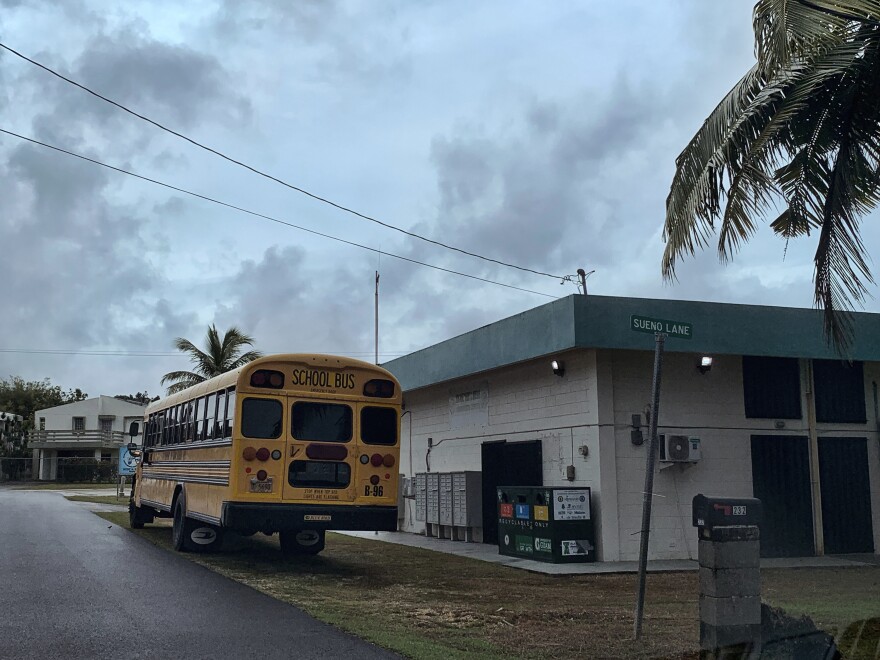A school bus waits at the side of the Mongmong-Toto-Maite community center to transport residents to public schools set up as emergency shelters, Tuesday, May 23, 2023, in Guam, ahead of Typhoon Mawar. (AP Photo/Grace Garces Bordallo)