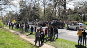 Protesters lined the street in front of the governor’s mansion waving American flags and holding signs as supporters honked in passing.