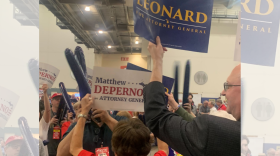 A group of people at the April 2022 Michigan Republican Party nominating convention. Some are holding signs supporting Matthew DePerno for attorney general and others are holding up signs supporting Tom Leonard for attorney general. 