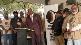 Executive Director of Circle of Brother Lyle Muhammad (center), 59, addressing a crowd outside the Stephen P. Clark Center in downtown Miami on March 3, 2026 with about 20 members of the violence prevention organization behind him.