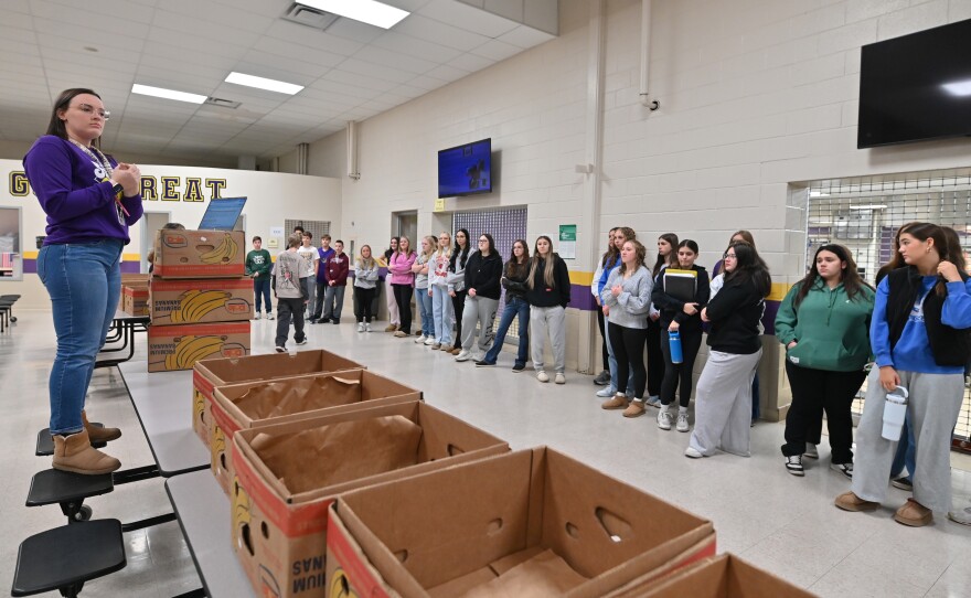 Forest City teacher Courtney Daniels gives students instructions for packing food boxes.