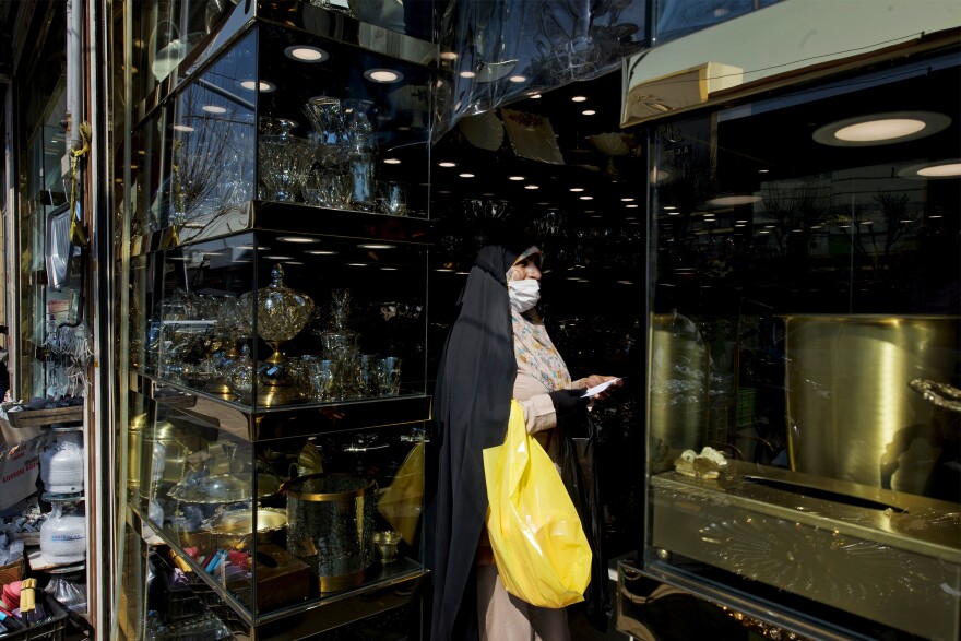 A woman wears a mask while shopping from a crystal shop in Shoosh Bazaar.