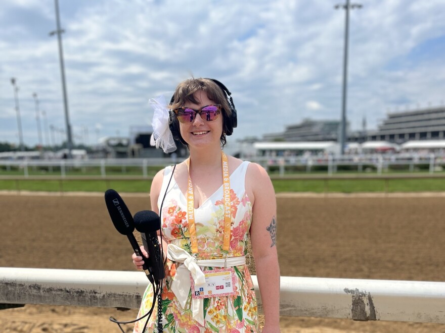A reporter holds recording equipment trackside at Churchill Downs.