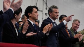 U.S. Defense Secretary Pete Hegseth, center right, with Japanese Prime Minister Sanae Takaichi, left, and Defense Minister Shinjiro Koizumi, gestures as they listen to President Donald Trump speak to members of the military aboard the USS George Washington, an aircraft carrier docked at an American naval base, in Yokosuka, south of Tokyo, Tuesday, Oct. 28, 2025. (AP Photo/Mark Schiefelbein)