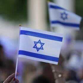 People wave Israeli flags during an empty Shabbat table event honoring those kidnapped by Hamas in Israel, Thursday, Nov. 2, 2023, at Temple Beth Sholom in Miami Beach, Florida. (Wilfredo Lee/AP)