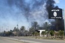 Smoke rises behind an Islamic State flag after a Nov. 24, 2014, battle with Iraqi security forces in Diyala province.