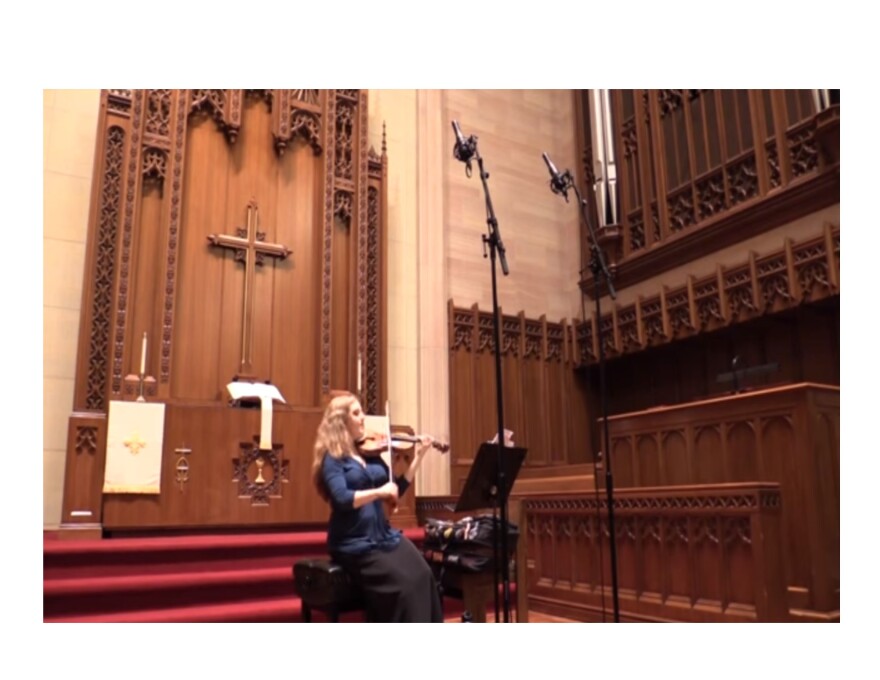 color photo of Rachel Barton Pine sitting down and playing her violin in the chancel area of St. Paul's UCC, Chicago