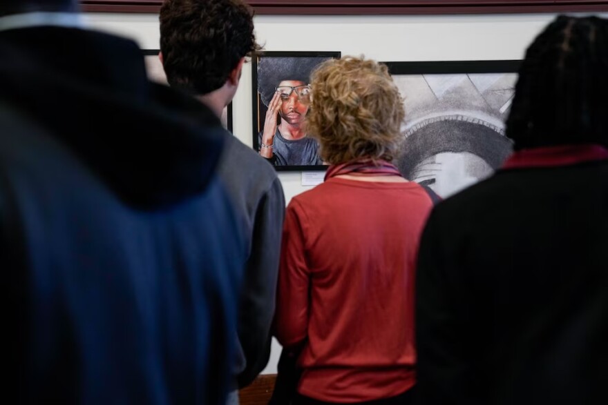 Event attendees take a closer look at some of the student artwork on display at the Eastside District Court building in May. (Ulysses Muñoz/The Baltimore Banner)