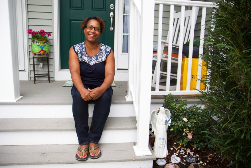 A person sits on the front steps of a home in front of a green door.