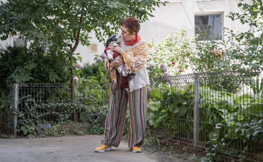 Daniela Draghici holding her dog, Mini, while on a walk in the backyard of her apartment building in Bucharest.