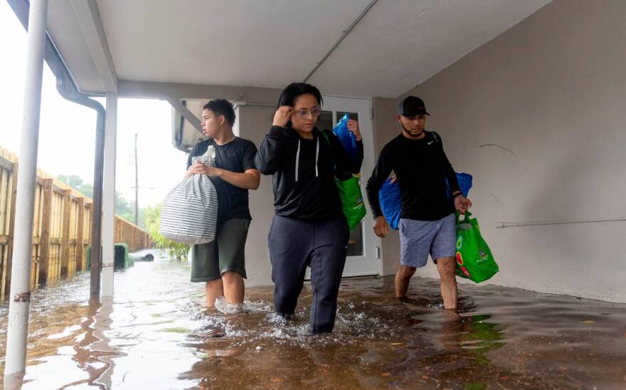 From left, Santiago Rojas, 15, Denis Mendez, 32, and Isain Lopez, 33, leave their flooded home in the Fort Lauderdale’s Edgewood neighborhood after a torrential downpour severely flooded streets, partially submerging houses and cars across South Florida.