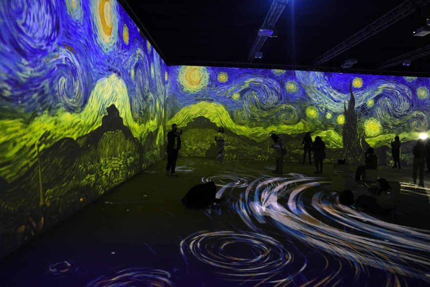 people walk around an immersive experience of van gogh's starry night