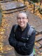 Emma Charles standing on an outdoor staircase with leaves scattered around.