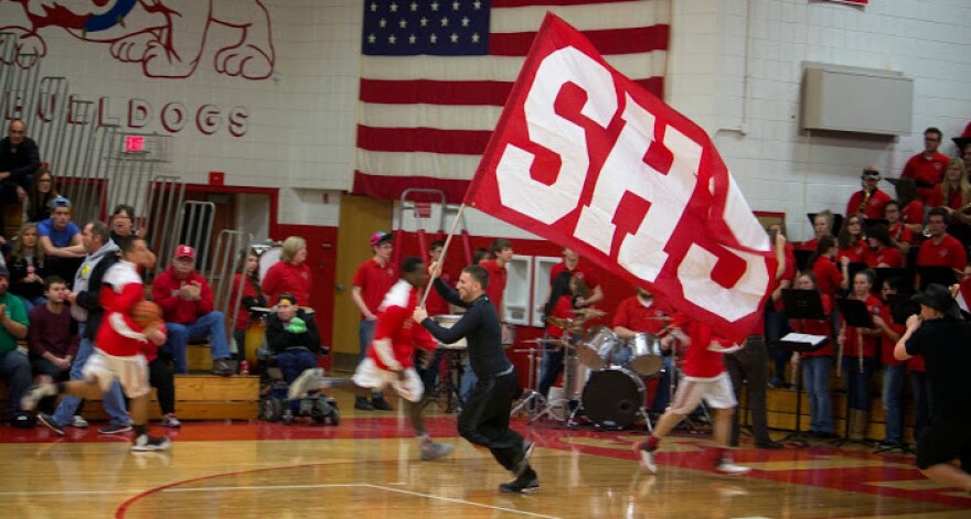 Student carrying school flag in gym