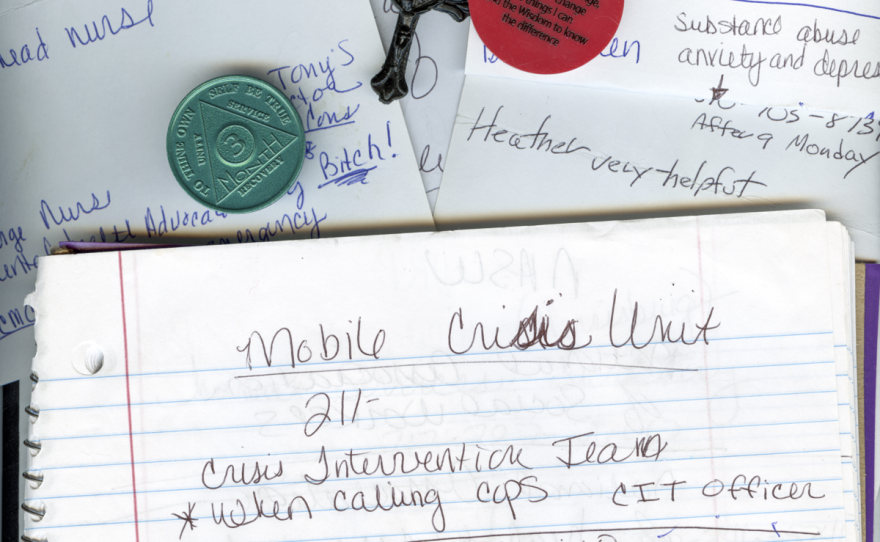 A photo of a notebook, paper, a cross, and sobriety chips.