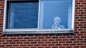 A resident of the Goodwin House senior living community, looks on as she listens to the DC area motown band "The Tribe" play a social distance concert in their parking lot in Arlington, Virginia, during the coronavirus pandemic on April 14, 2020. (ANDREW CABALLERO-REYNOLDS/AFP via Getty Images)