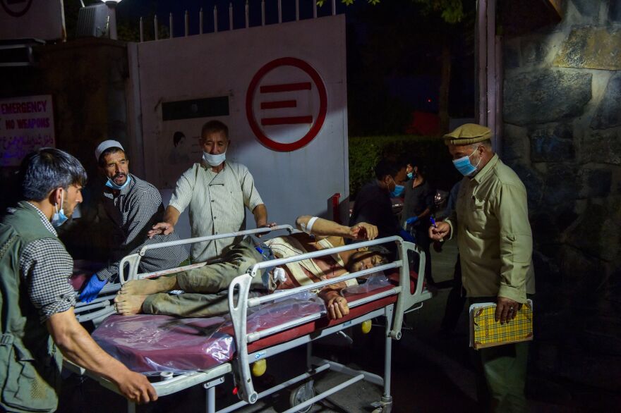 <strong>Thurs., Aug. 26: </strong>Medical and hospital staff bring an injured man for treatment after two powerful explosions outside the airport in Kabul.